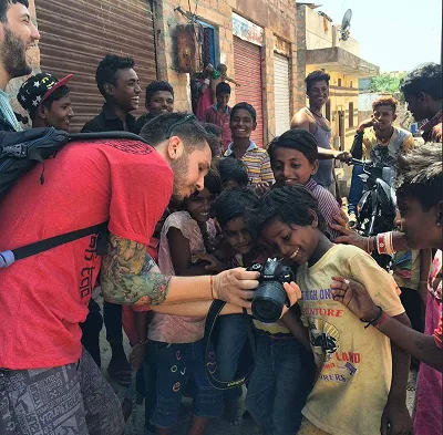 Fede sacando una foto en una calle, rodeado de chicos que se asoman a mirar la pantalla de la cámara